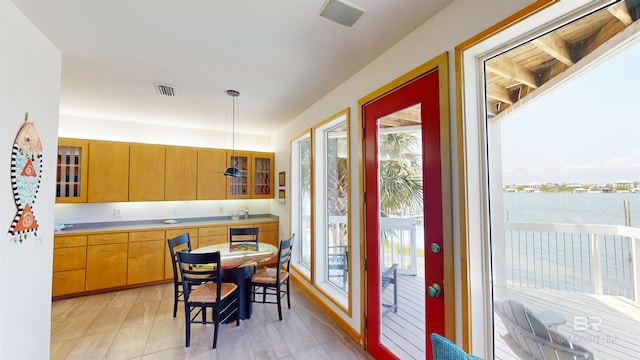 kitchen with decorative light fixtures, a wealth of natural light, light tile flooring, and a water view