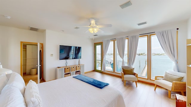 bedroom featuring ceiling fan, access to exterior, light wood-type flooring, and a water view