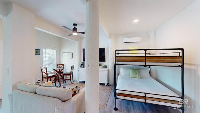 bedroom with a wall mounted AC, hardwood / wood-style floors, and ceiling fan