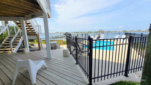 deck featuring a water view and a fenced in pool