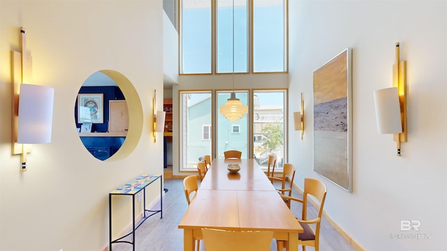 dining area featuring wood-type flooring and a high ceiling