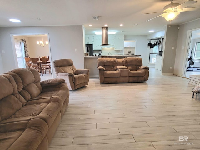 living room featuring ceiling fan with notable chandelier and light wood-type flooring