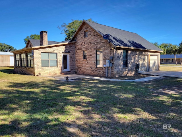 back of property featuring a garage and a lawn