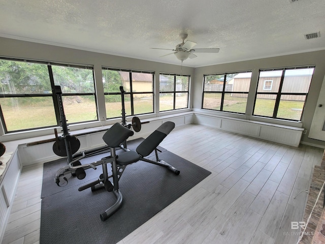 exercise area featuring ceiling fan, plenty of natural light, crown molding, and light wood-type flooring