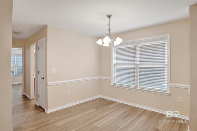 unfurnished room featuring light hardwood / wood-style floors and an inviting chandelier