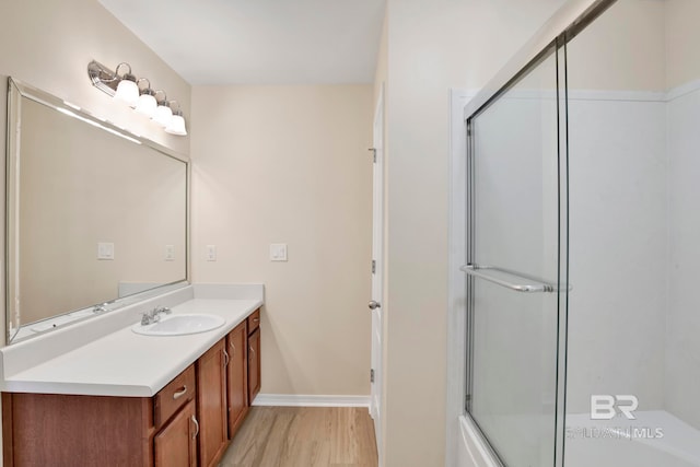 bathroom with hardwood / wood-style floors, vanity, and bath / shower combo with glass door