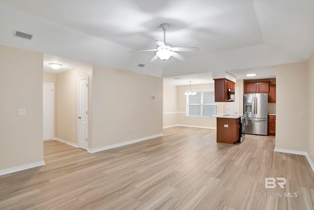 unfurnished living room featuring ceiling fan with notable chandelier and light hardwood / wood-style flooring