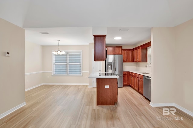 kitchen with stainless steel appliances, sink, a notable chandelier, a kitchen island, and hanging light fixtures