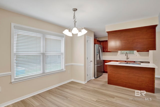 kitchen featuring stainless steel fridge, light hardwood / wood-style flooring, an inviting chandelier, and hanging light fixtures