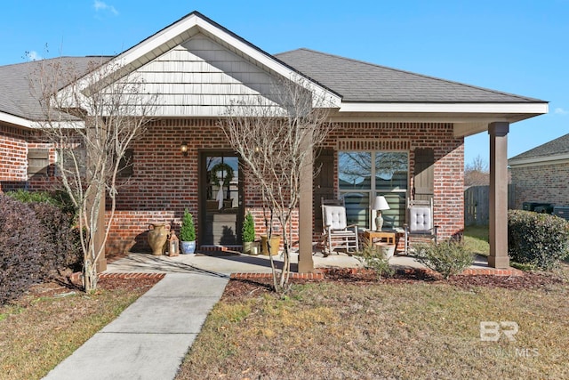 view of front of home with a shingled roof, a front lawn, a patio, and brick siding