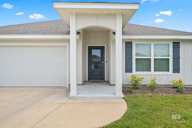 24193 Lanai Ln, Elberta, AL 36530 - property entrance featuring roof with shingles, board and batten siding, an attached garage, concrete driveway, and a yard