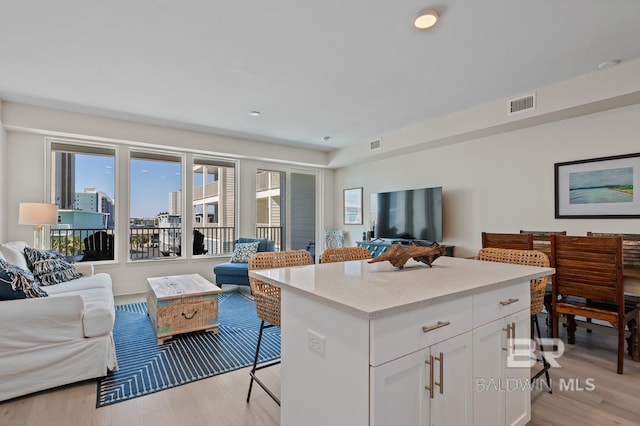 kitchen with a center island, a breakfast bar, light wood-type flooring, and white cabinets