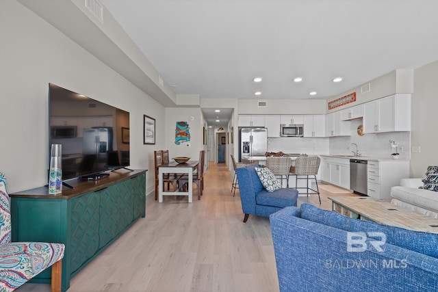 living room with sink and light hardwood / wood-style flooring