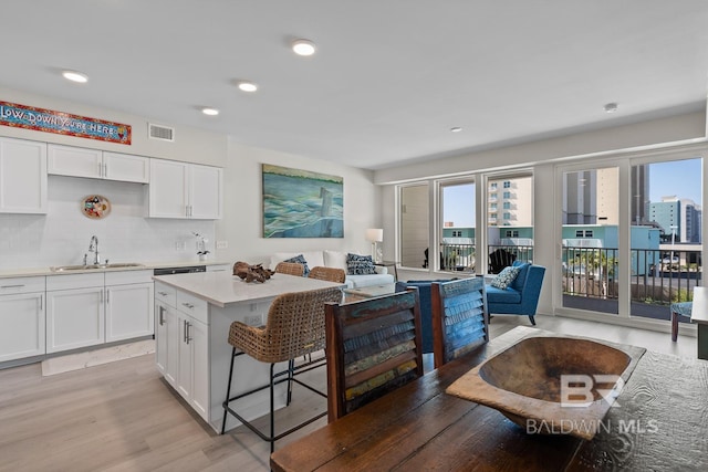 kitchen featuring white cabinetry, light hardwood / wood-style floors, sink, and a center island