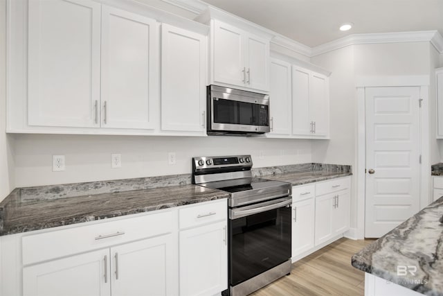 kitchen featuring white cabinetry, dark stone counters, light wood-type flooring, and appliances with stainless steel finishes