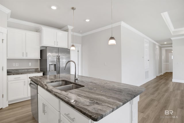 kitchen with a center island with sink, a sink, light wood-style floors, appliances with stainless steel finishes, and crown molding