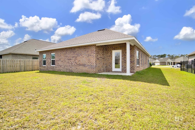 back of property with a lawn, brick siding, and fence