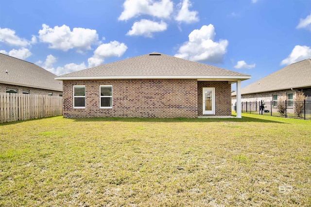 back of property featuring a lawn, brick siding, and a fenced backyard