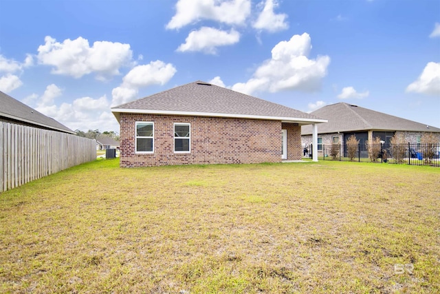 back of property featuring brick siding, central air condition unit, a yard, and fence