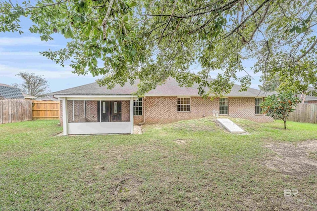 rear view of property featuring a sunroom and a yard