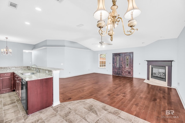 kitchen featuring light stone countertops, sink, lofted ceiling, ceiling fan with notable chandelier, and hardwood / wood-style flooring