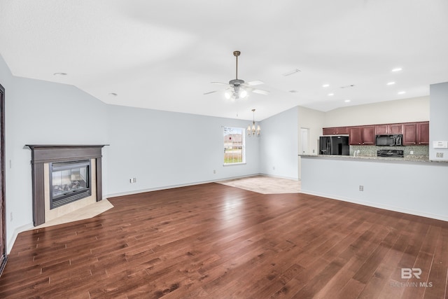 unfurnished living room featuring lofted ceiling, ceiling fan with notable chandelier, and dark hardwood / wood-style floors