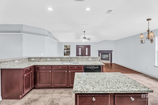 kitchen featuring sink, dishwasher, light stone counters, a kitchen island with sink, and ceiling fan with notable chandelier