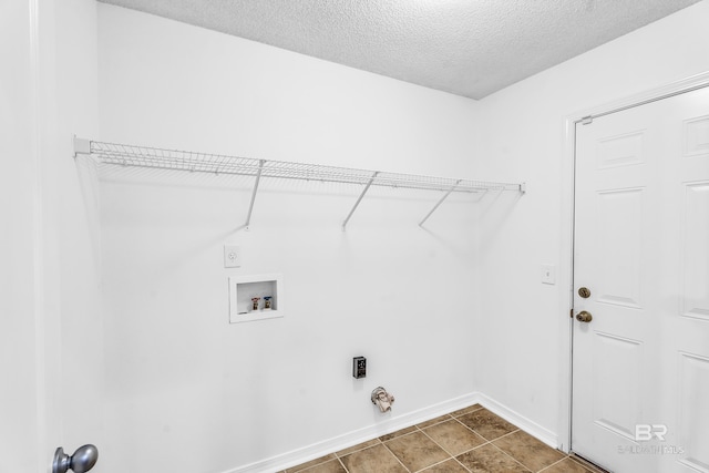 clothes washing area featuring electric dryer hookup, tile patterned floors, hookup for a gas dryer, washer hookup, and a textured ceiling