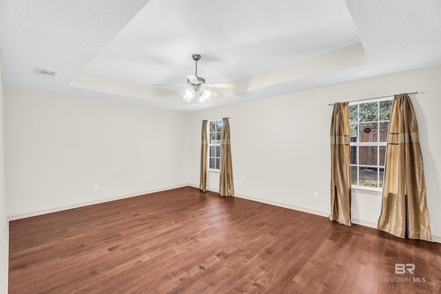 spare room with a tray ceiling, ceiling fan, a textured ceiling, and dark hardwood / wood-style floors