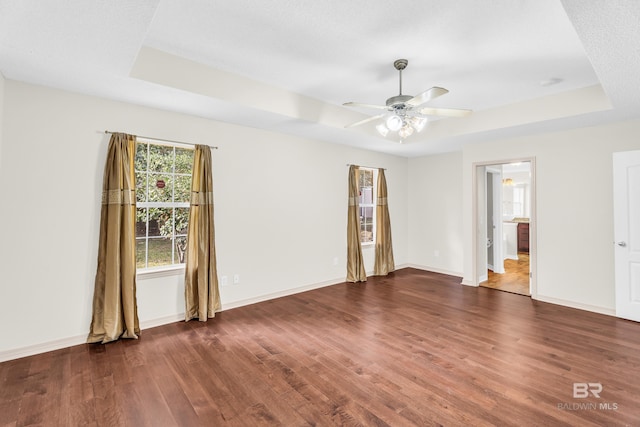 interior space featuring a textured ceiling, dark hardwood / wood-style flooring, a raised ceiling, and ceiling fan