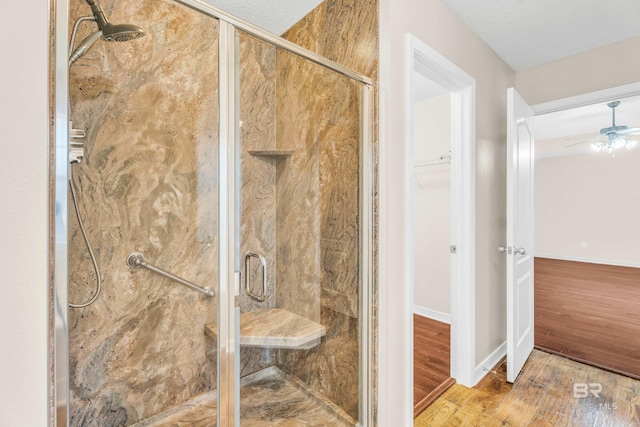 bathroom featuring ceiling fan, a shower with door, a textured ceiling, and hardwood / wood-style flooring