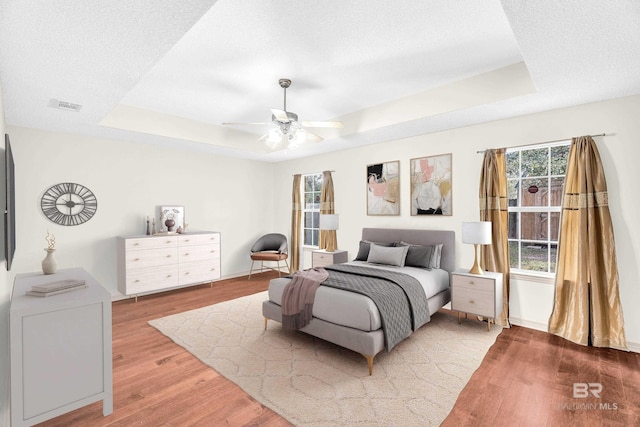 bedroom featuring a raised ceiling, ceiling fan, and hardwood / wood-style flooring