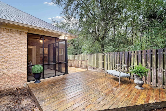 wooden terrace with a fenced backyard and a sunroom