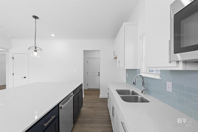4645 Casablanca Dr, Orange Beach, AL 36561 - kitchen with stainless steel appliances, a sink, dark wood-type flooring, white cabinets, and ornamental molding