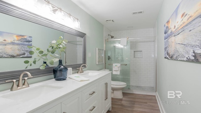 bathroom featuring a sink, toilet, wood finished floors, and a shower stall