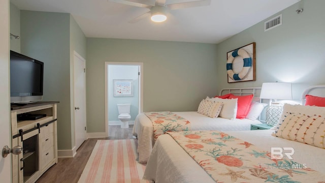 bedroom with visible vents, ensuite bathroom, a ceiling fan, wood finished floors, and baseboards