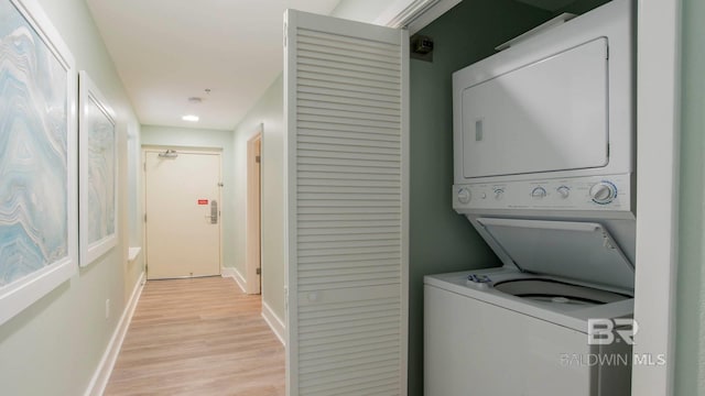 washroom with baseboards, light wood-style floors, laundry area, and stacked washer / dryer