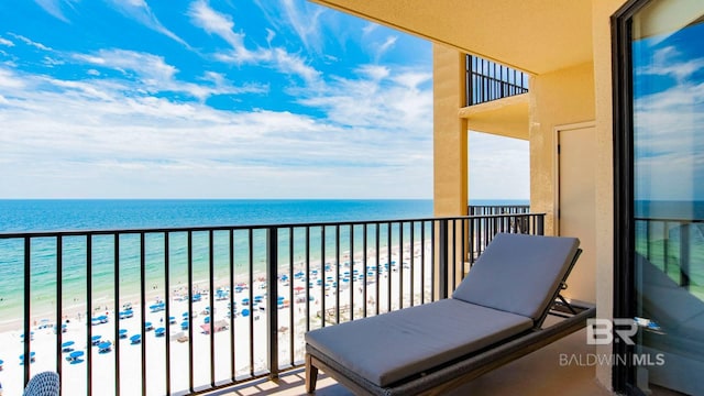 balcony with a water view and a view of the beach