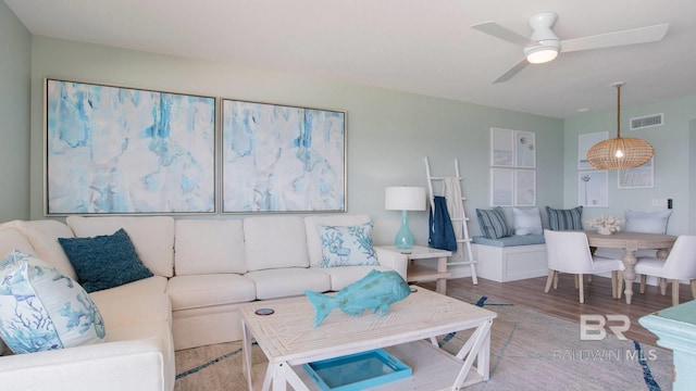 living area featuring visible vents, a ceiling fan, and wood finished floors