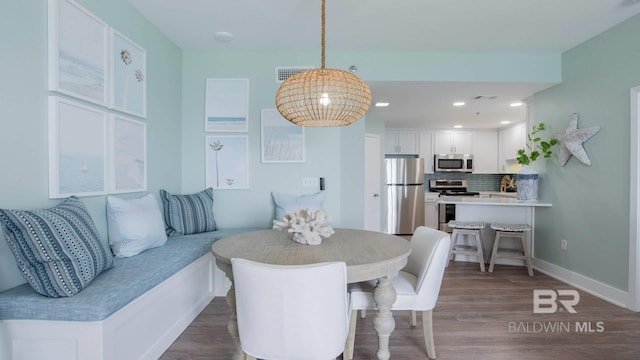 dining area featuring visible vents, baseboards, and wood finished floors