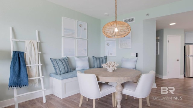 dining area featuring wood finished floors, visible vents, and baseboards