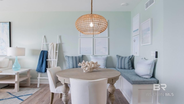 dining room featuring a notable chandelier, baseboards, visible vents, and wood finished floors