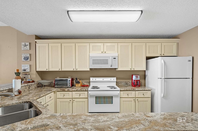 kitchen with a toaster, white appliances, cream cabinets, and a sink