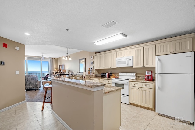 kitchen featuring white appliances, a breakfast bar area, visible vents, a peninsula, and light tile patterned flooring