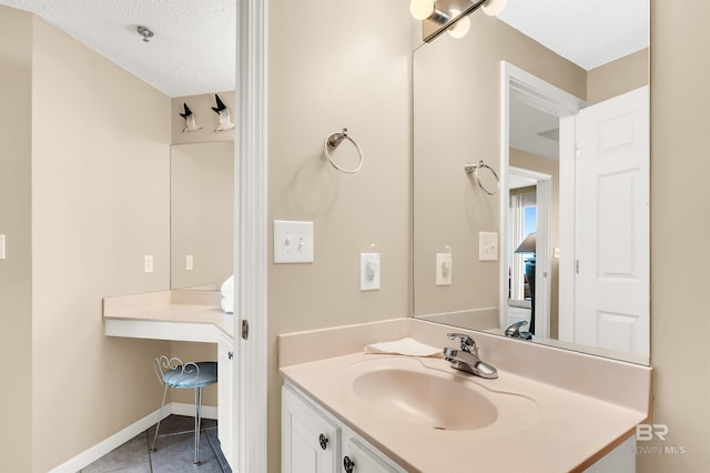 bathroom with tile patterned flooring, a textured ceiling, vanity, and baseboards