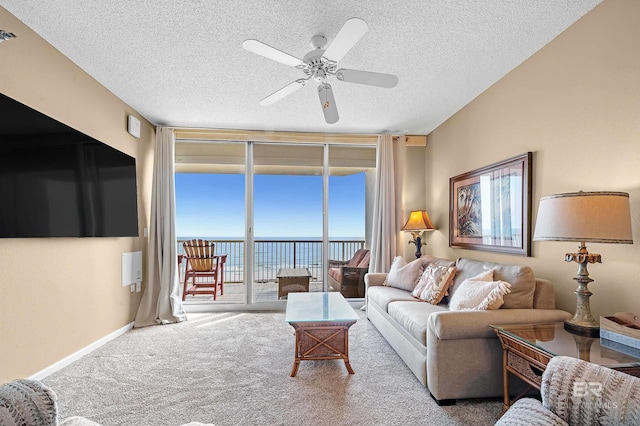 living room featuring baseboards, carpet floors, ceiling fan, floor to ceiling windows, and a textured ceiling