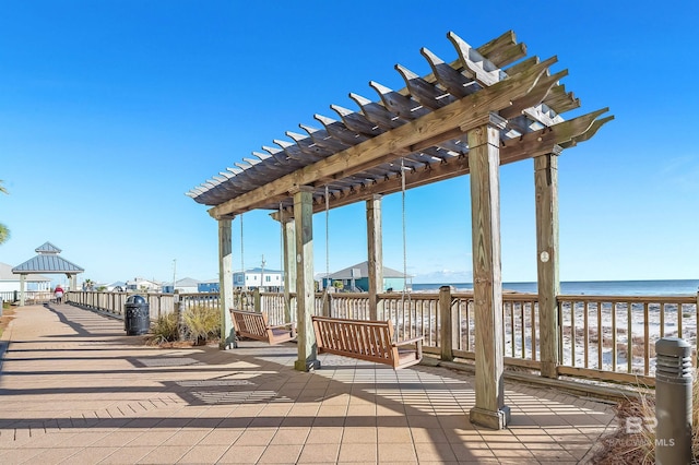 view of community with a beach view, a pergola, and a water view