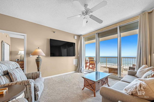 living room featuring expansive windows, a ceiling fan, baseboards, a textured ceiling, and carpet flooring