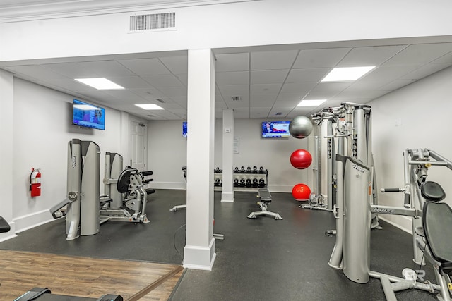 exercise room with visible vents, a paneled ceiling, and baseboards