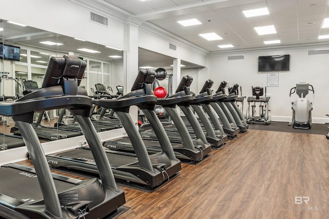 exercise room featuring visible vents, ornamental molding, a drop ceiling, wood finished floors, and baseboards